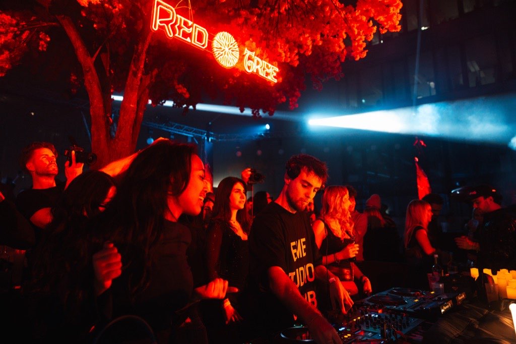 The Red Tree above a dense crowd, guests filming on their phones